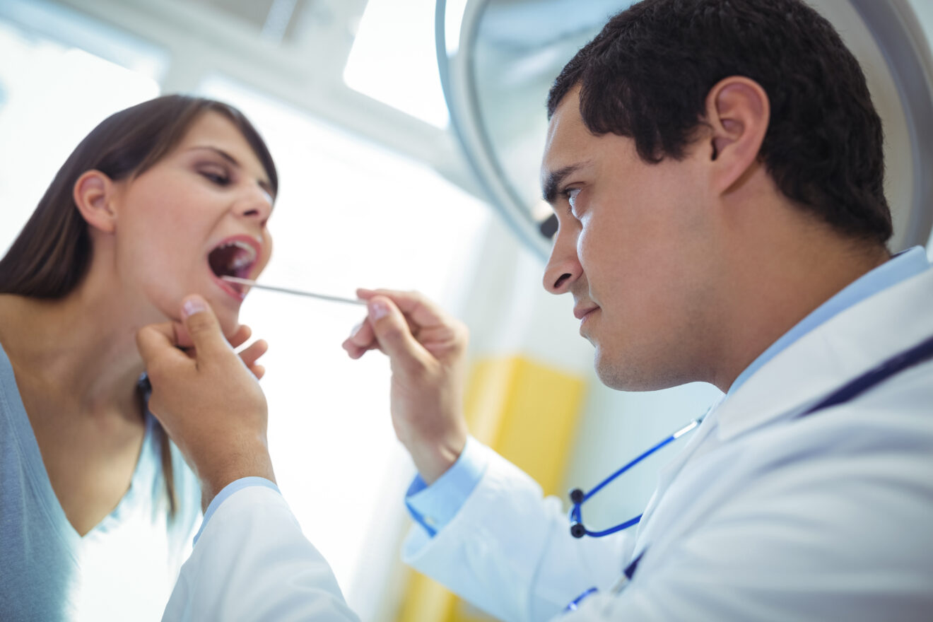 doctor examining female patients mouth in the hospital